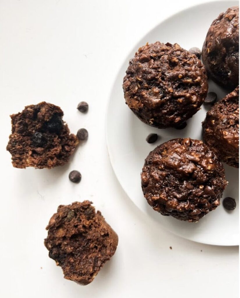 Muffins au chocolat avec des pépites de chocolat, sur une assiette blanche, avec un muffin cassé à côté.